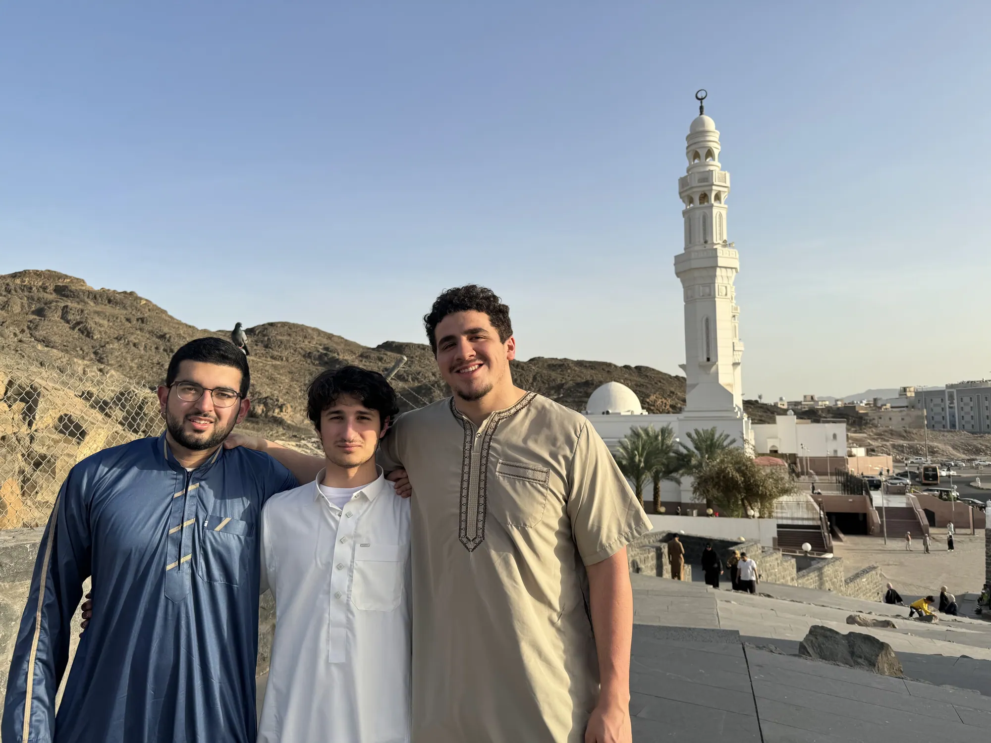 Three students standing on high ground overlooking the rocky landscape around Mount Uhud.