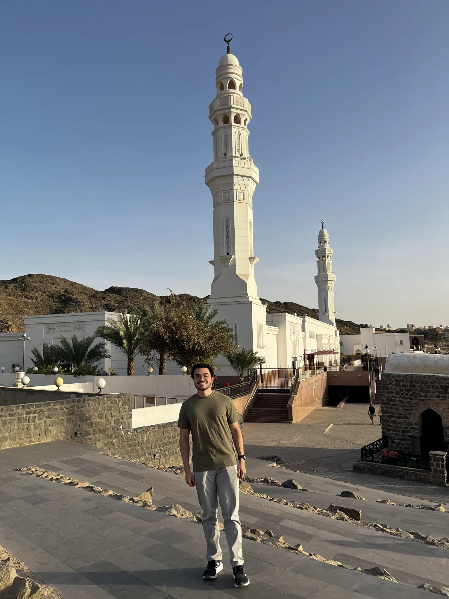 A student in white ihram garments standing outside the miqat mosque.