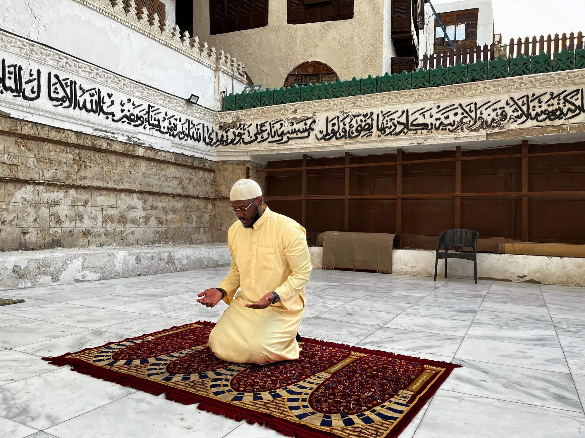 A student with raised hands in quiet personal supplication during the journey in Jeddah.