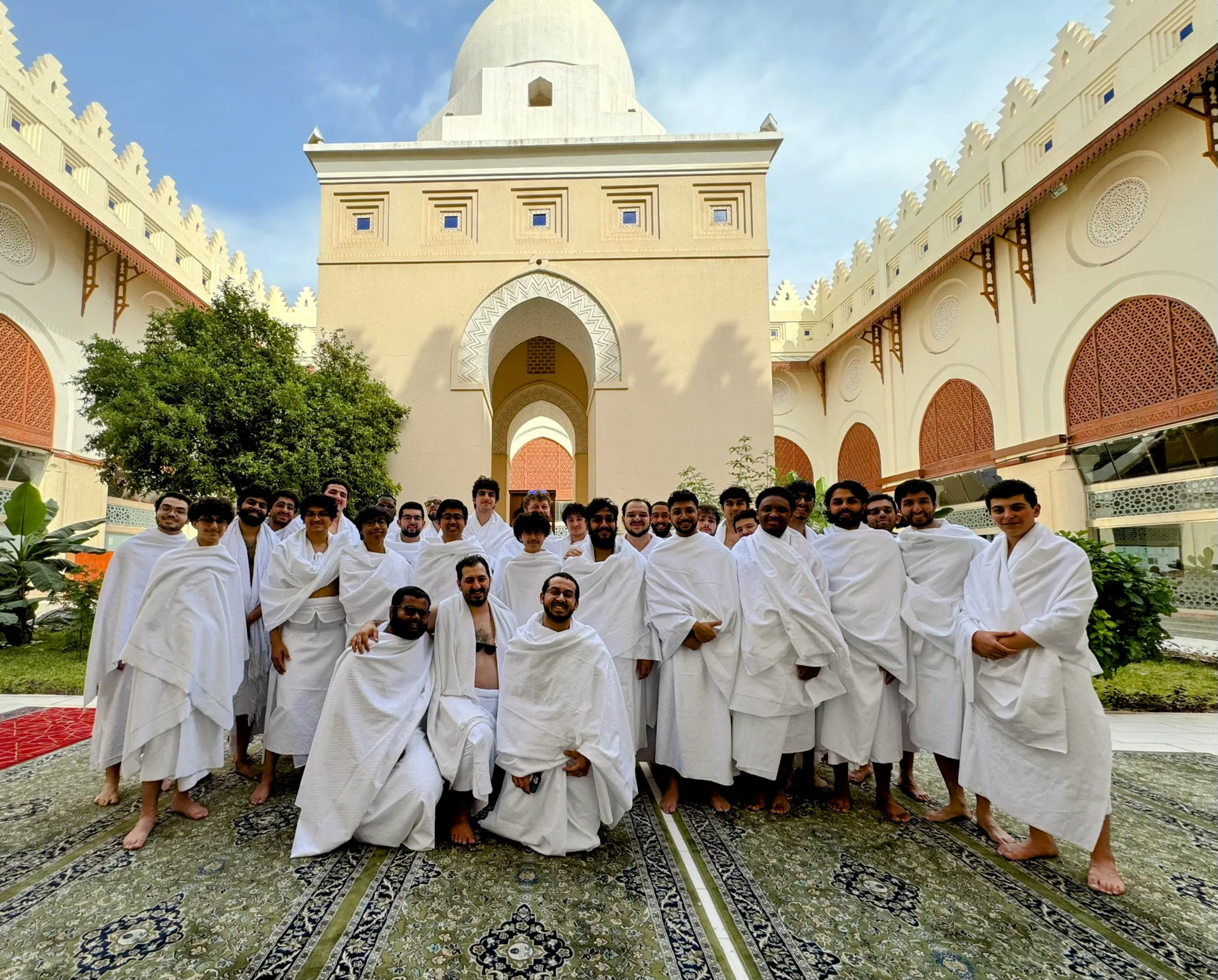 The cohort gathered in white ihram garments at the miqat before beginning Umrah.