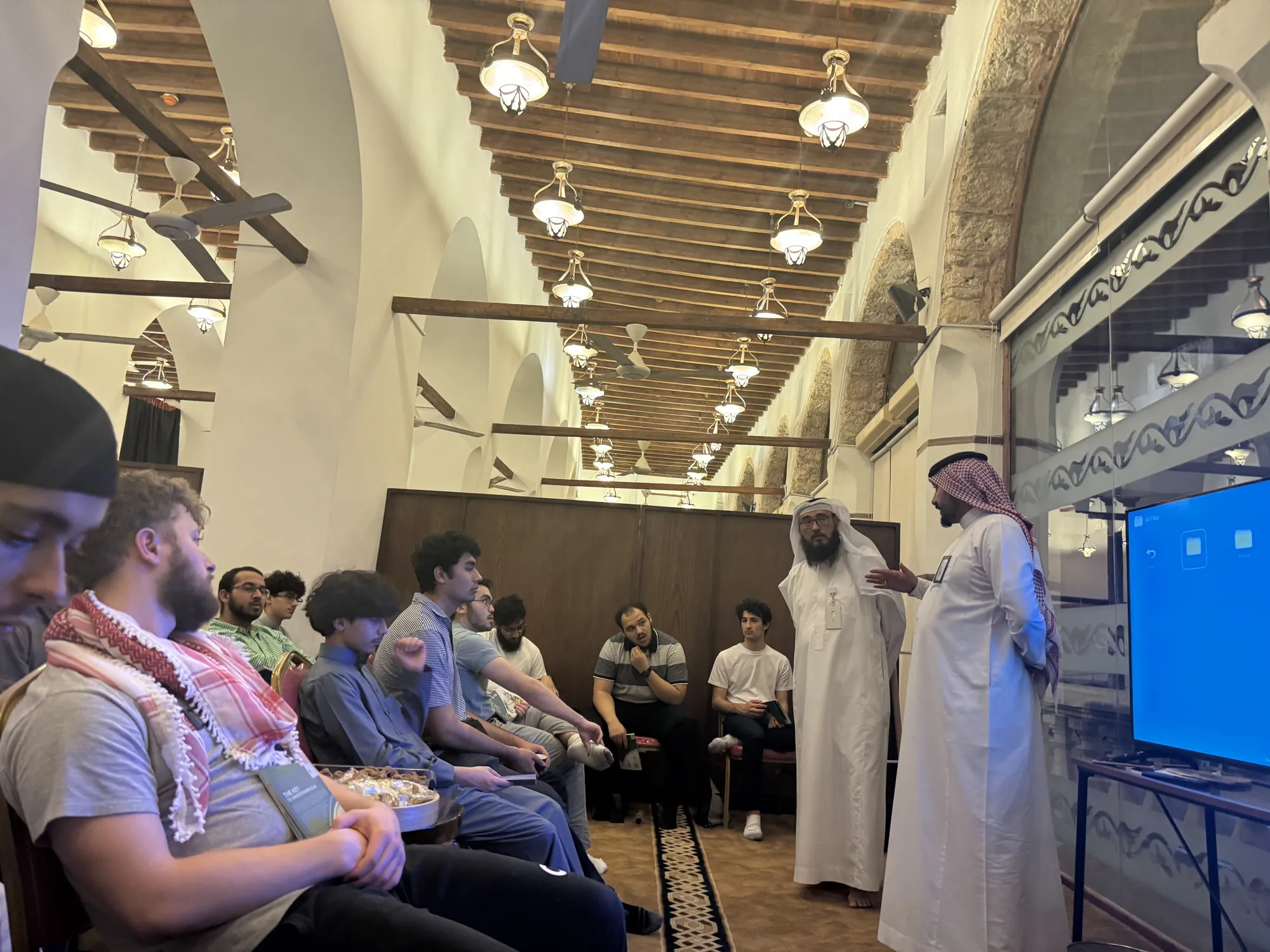 Students seated in a small circle listening to a lesson on Islamic law in a historic mosque.