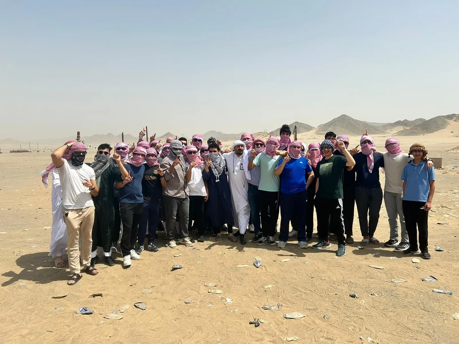 A group of students standing together in open desert during an excursion near Jeddah.